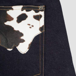 Close-up of LUXENK© Cow Pocket denim jeans by Hideout, showing the cow-shaped pocket detail on the stylish blue bottoms.
