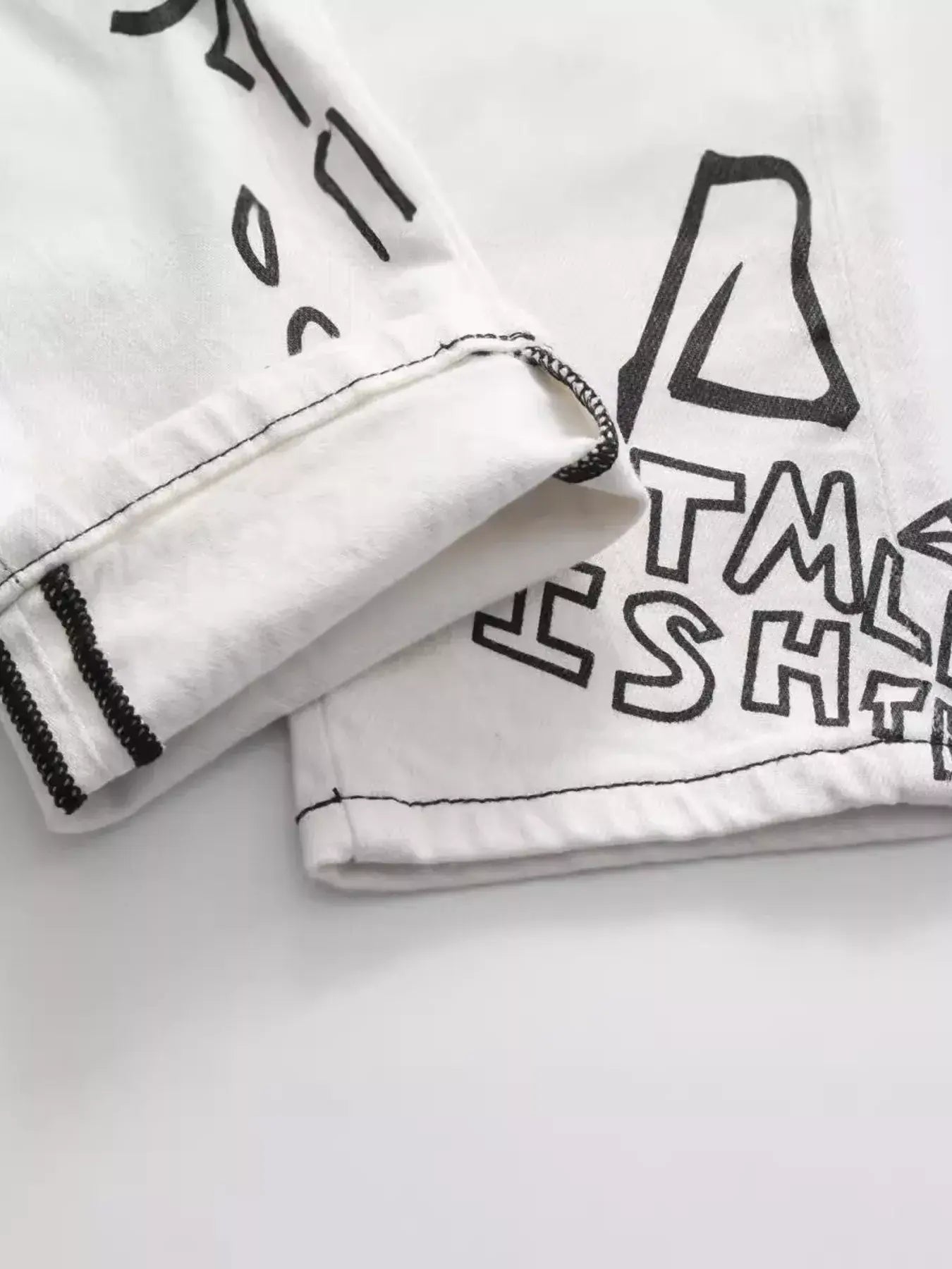 White Luxenk Graffiti Slim Jeans by Trendsi, showcasing a slim fit design with subtle graffiti-style detailing visible in the image.