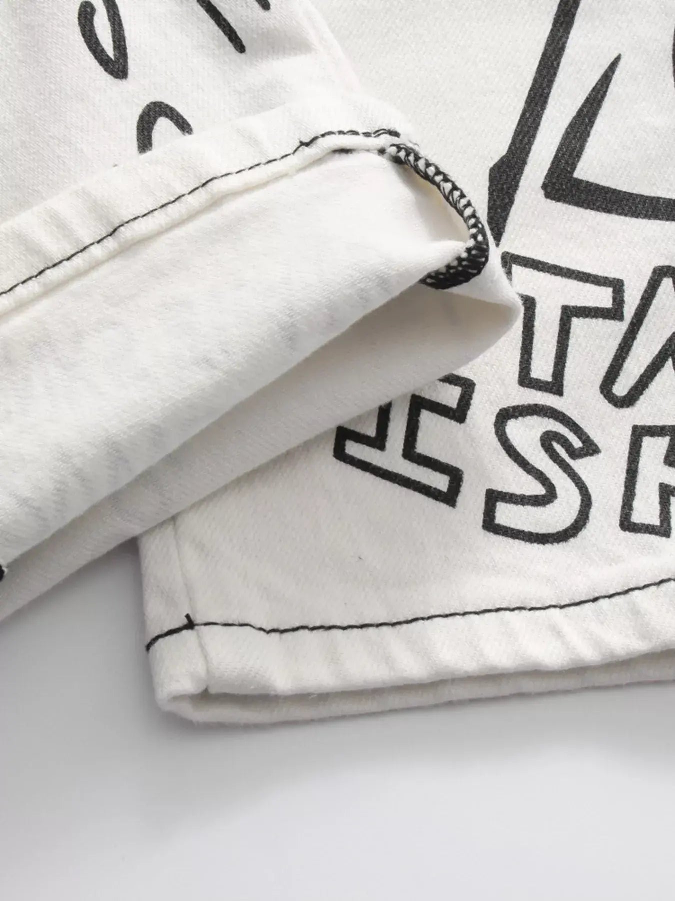 White Luxenk© "Graffiti Slim" jeans by Trendsi, showing the slim-fit design and trendy graffiti-inspired detailing.