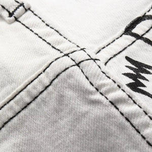 White Luxenk Graffiti Slim Jeans by Trendsi, showing a close-up of the fitted denim with subtle graffiti-style stitching.