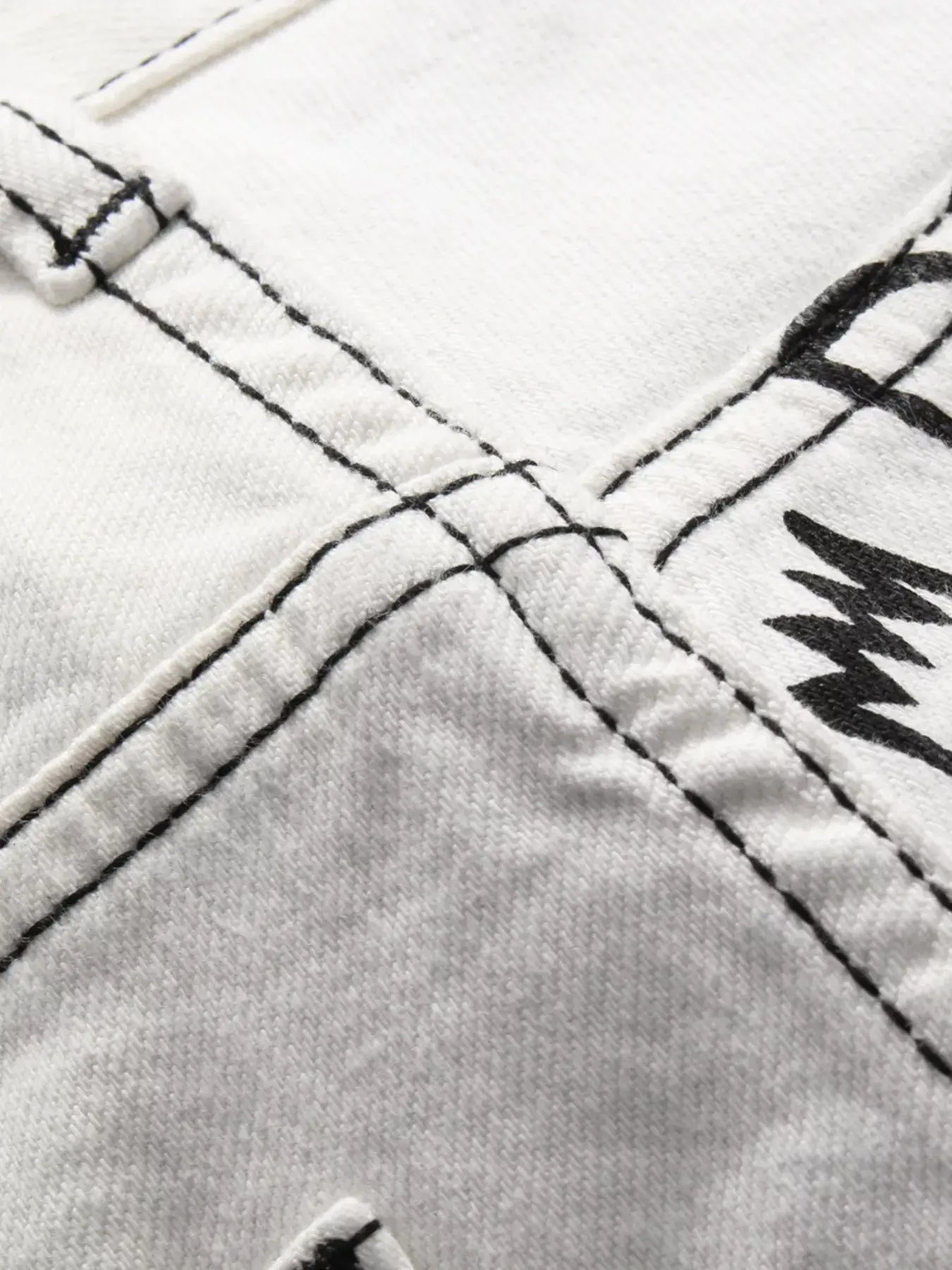 White Luxenk Graffiti Slim Jeans by Trendsi, showing a close-up of the fitted denim with subtle graffiti-style stitching.